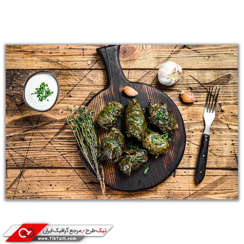 تصویر با کیفیت چند دلمه با سس روی سینی چوبی