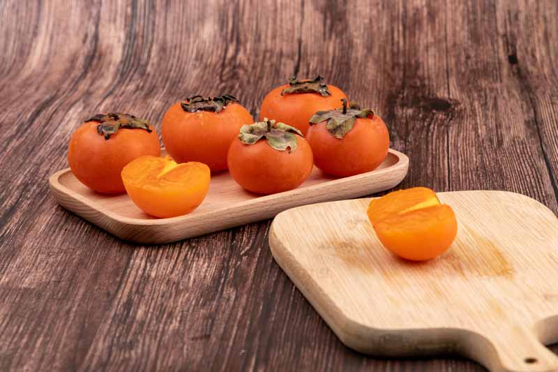 دانلود تصویر خرمالو ها روی ظرف چوبی