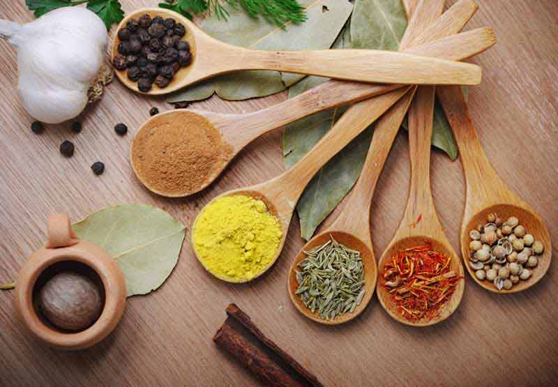 عکس لارج فرمت ادویه جات داخل قاشق چوبی روی میز چوبی